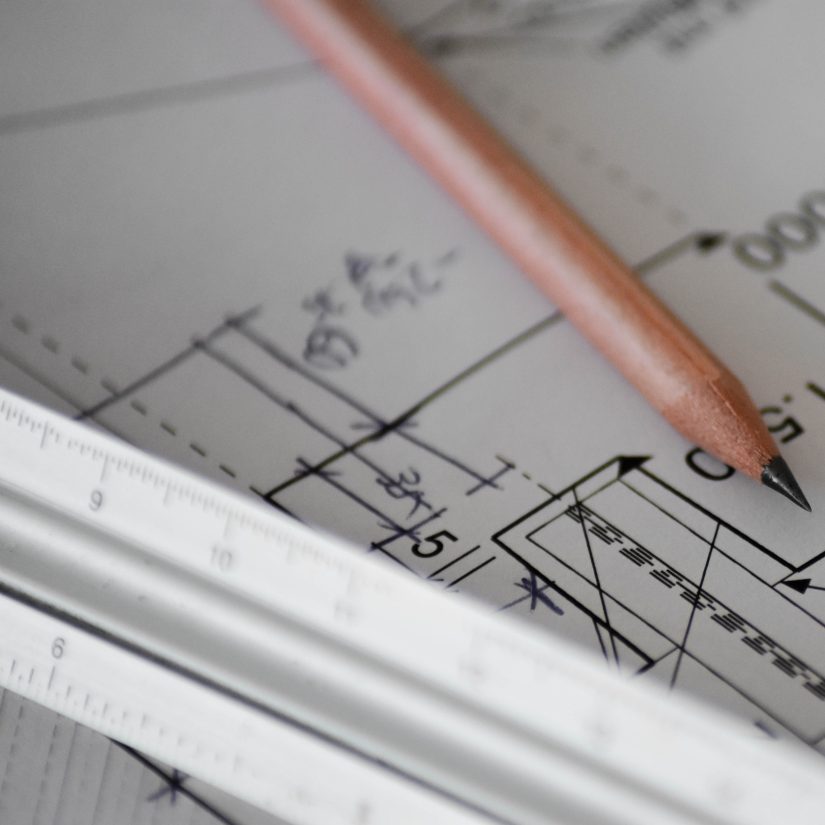 A pencil sits on top of a large diagram or blueprint.