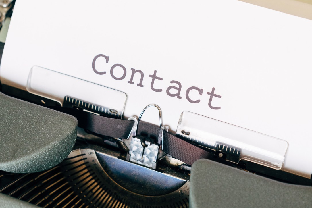 A closeup image of a typewriter, with the single word "Contact" typed out on the page.