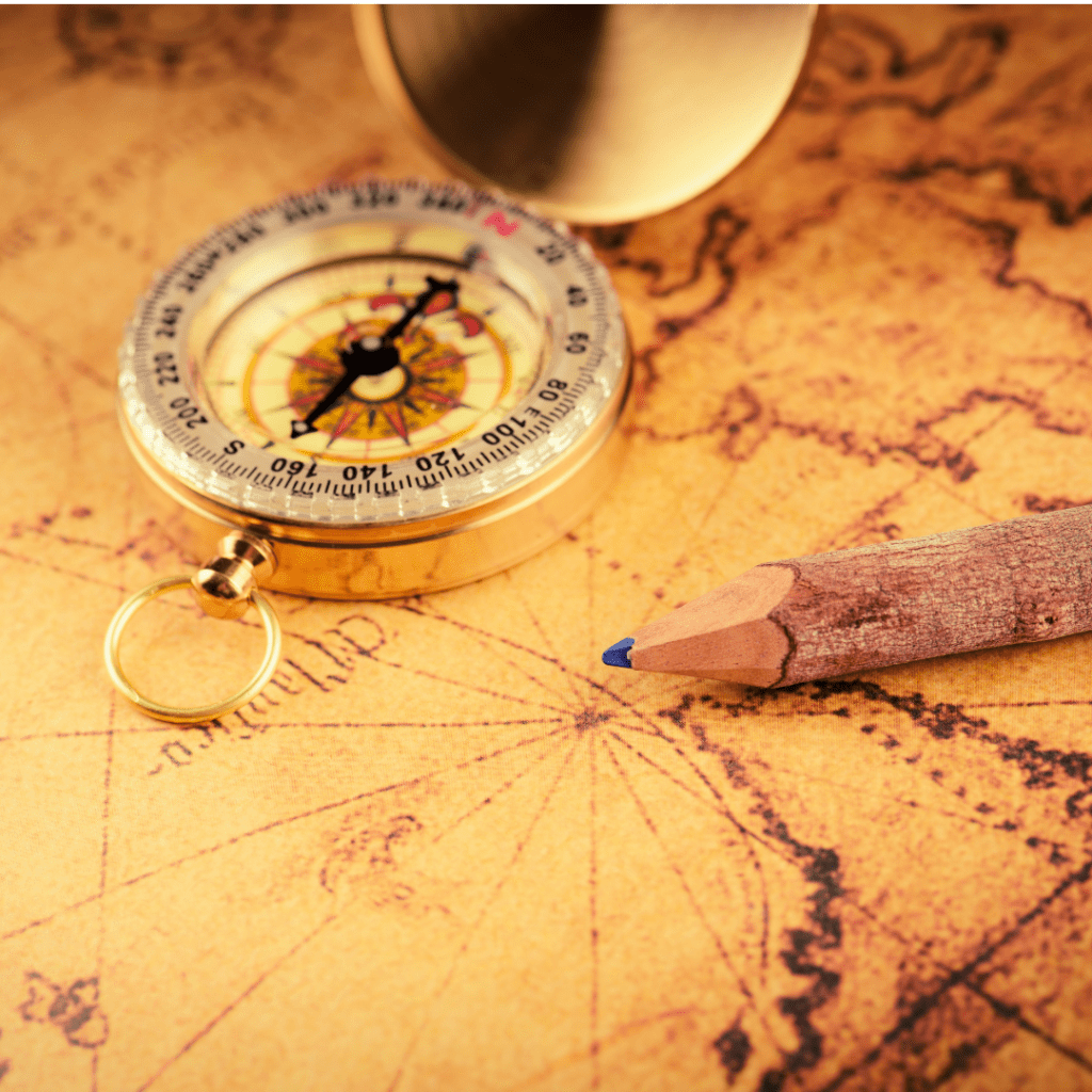 A pencil and magnetic compass sit together on a fancy, old-fashioned map.