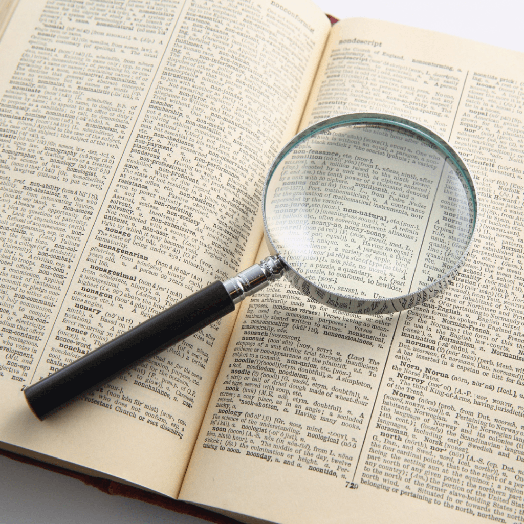 A magnifying glass sits on top of a book page densely packed with words.